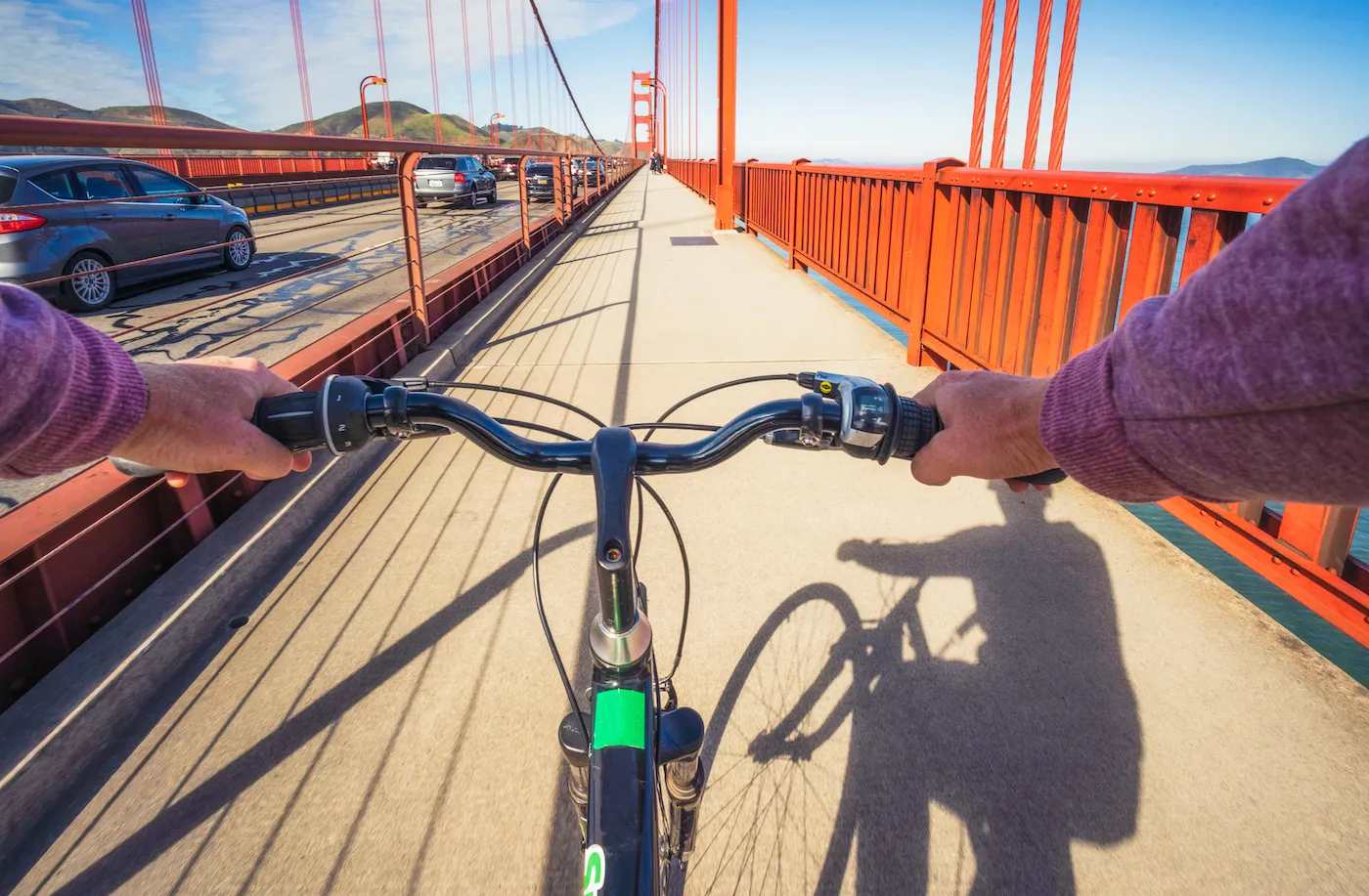 A view from the perspective of a cyclist crossing the Golden Gate Bridge on a sunny day.
