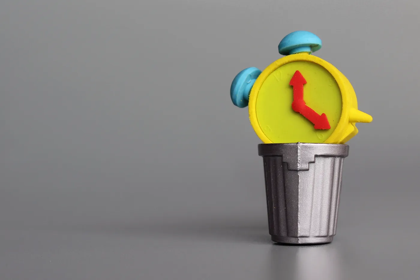 Wasting time concept. Alarm clock inside garbage can. Copy space for text.