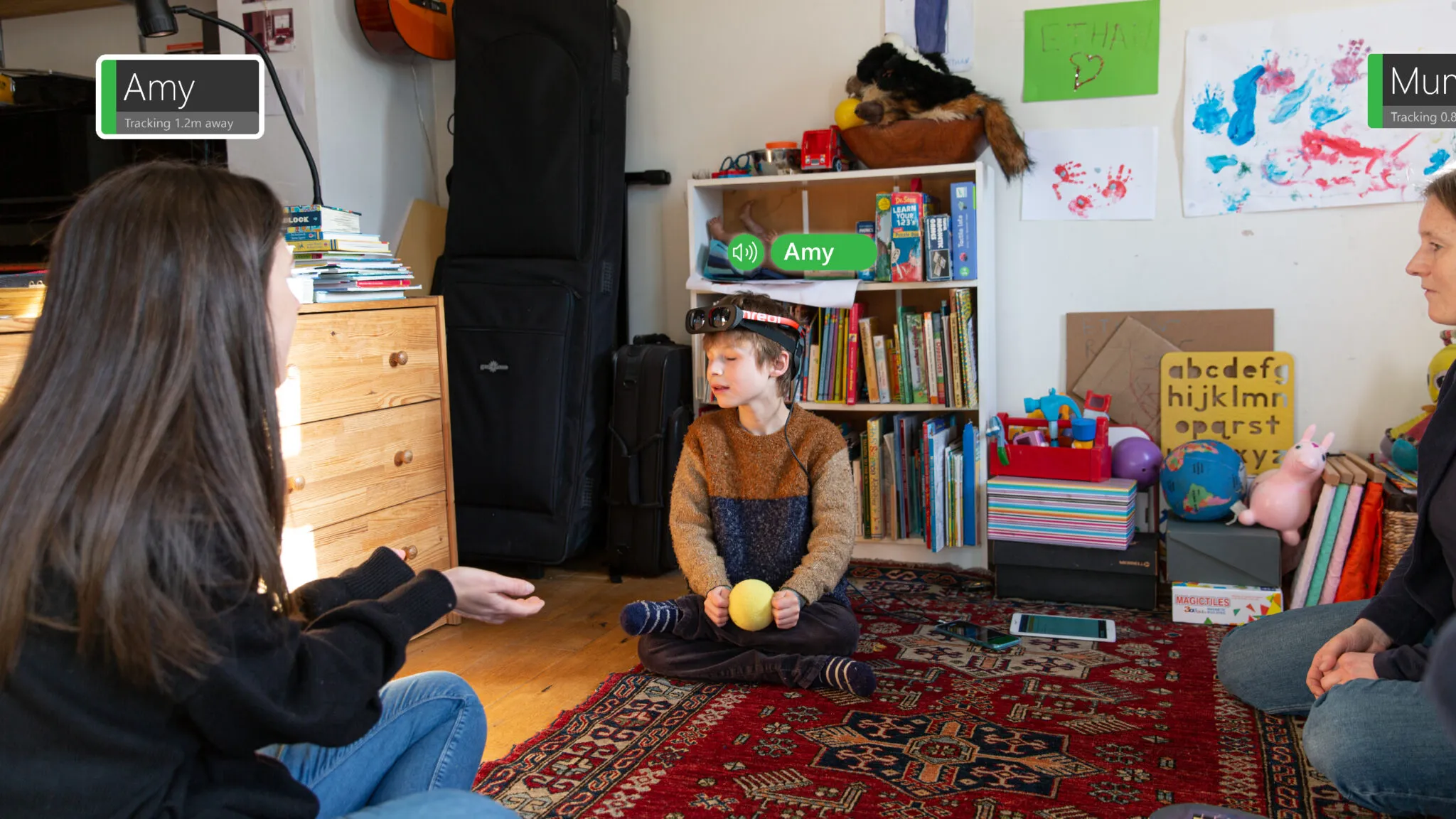 A young blind boy sits in a group wearing the PeopleLens prototype.