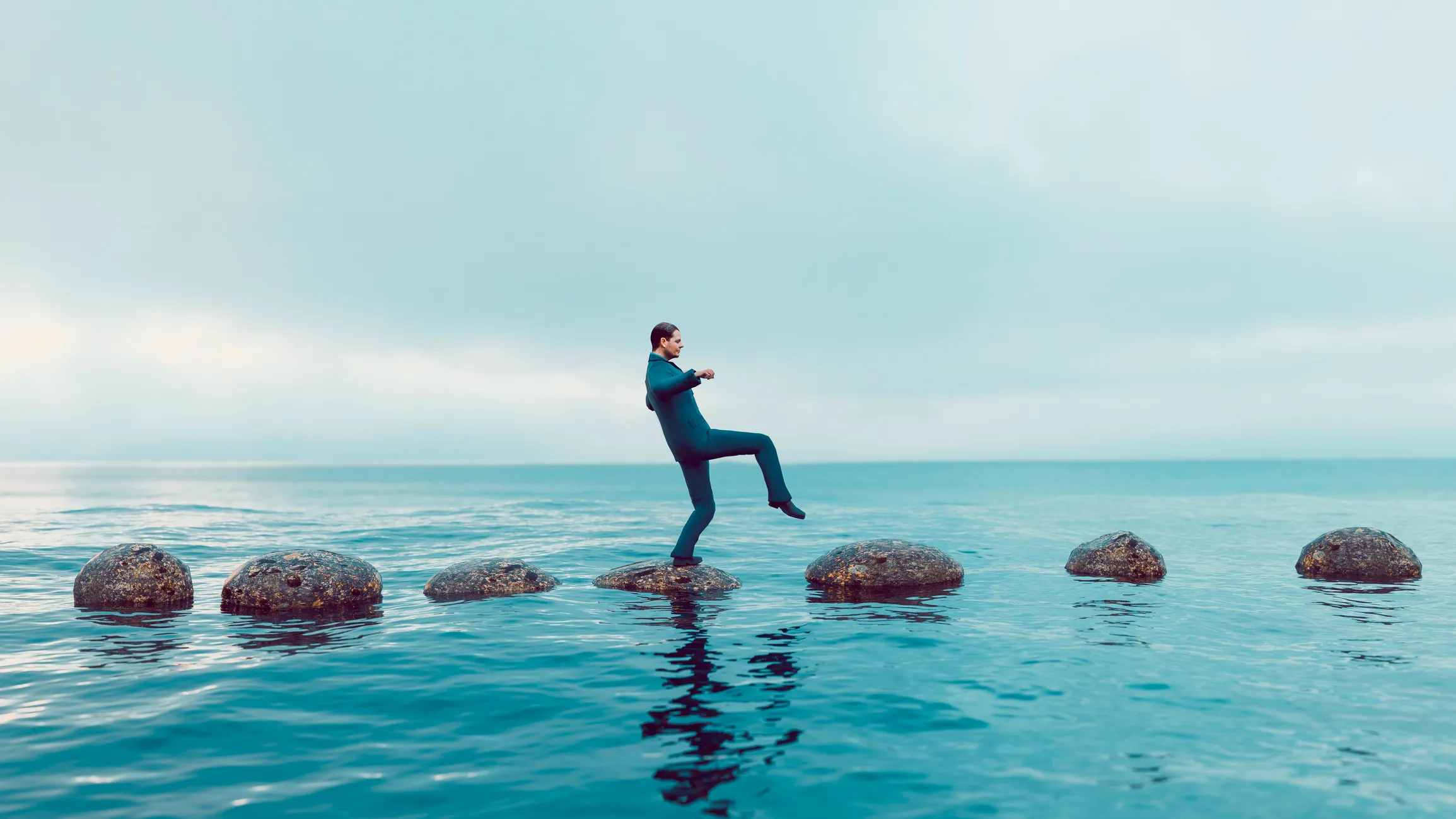 Man walks carefully on a path of small rocks in the middle of the sea; private equity must deal carefully with sanctions