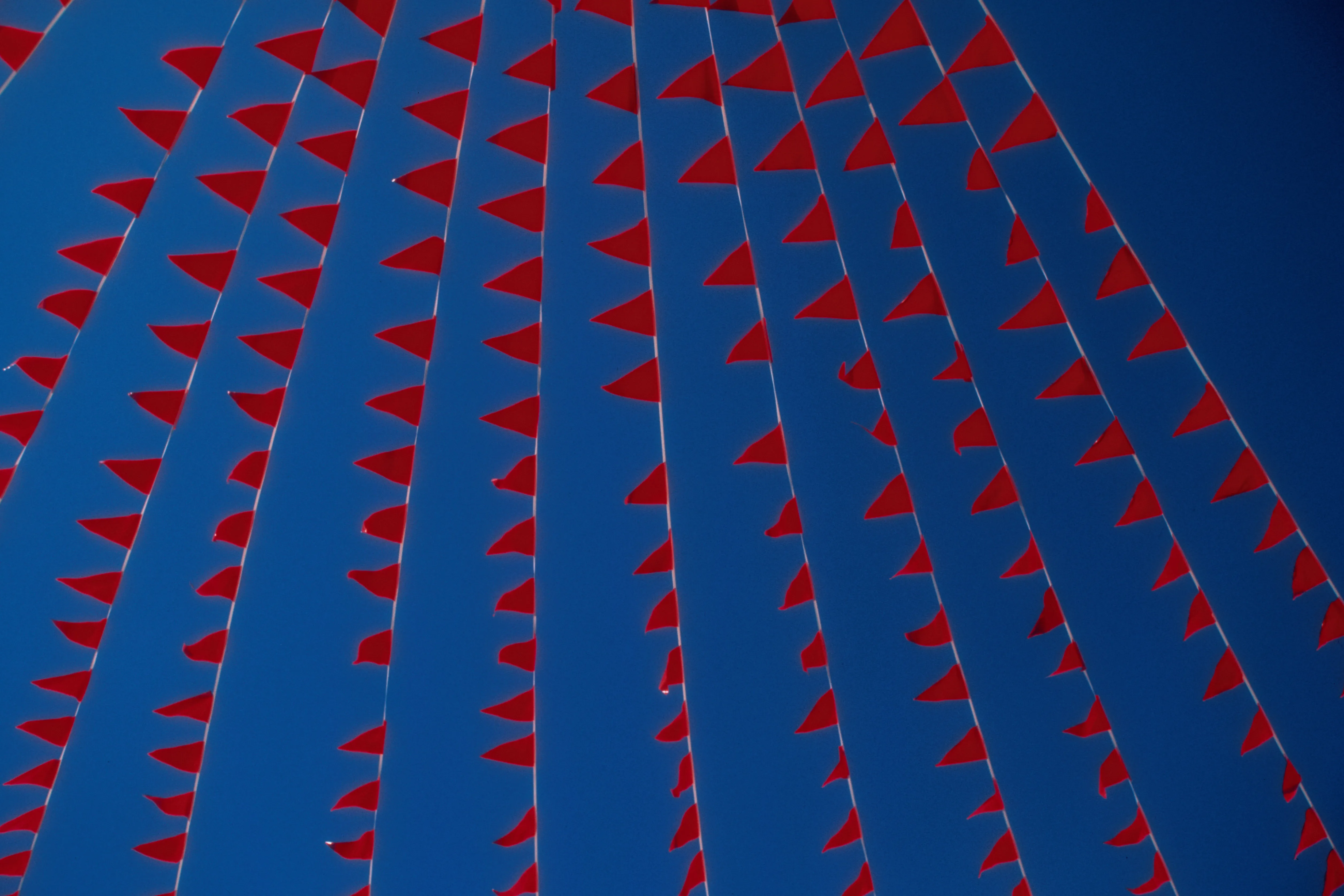 Image of red flags against a blue sky.