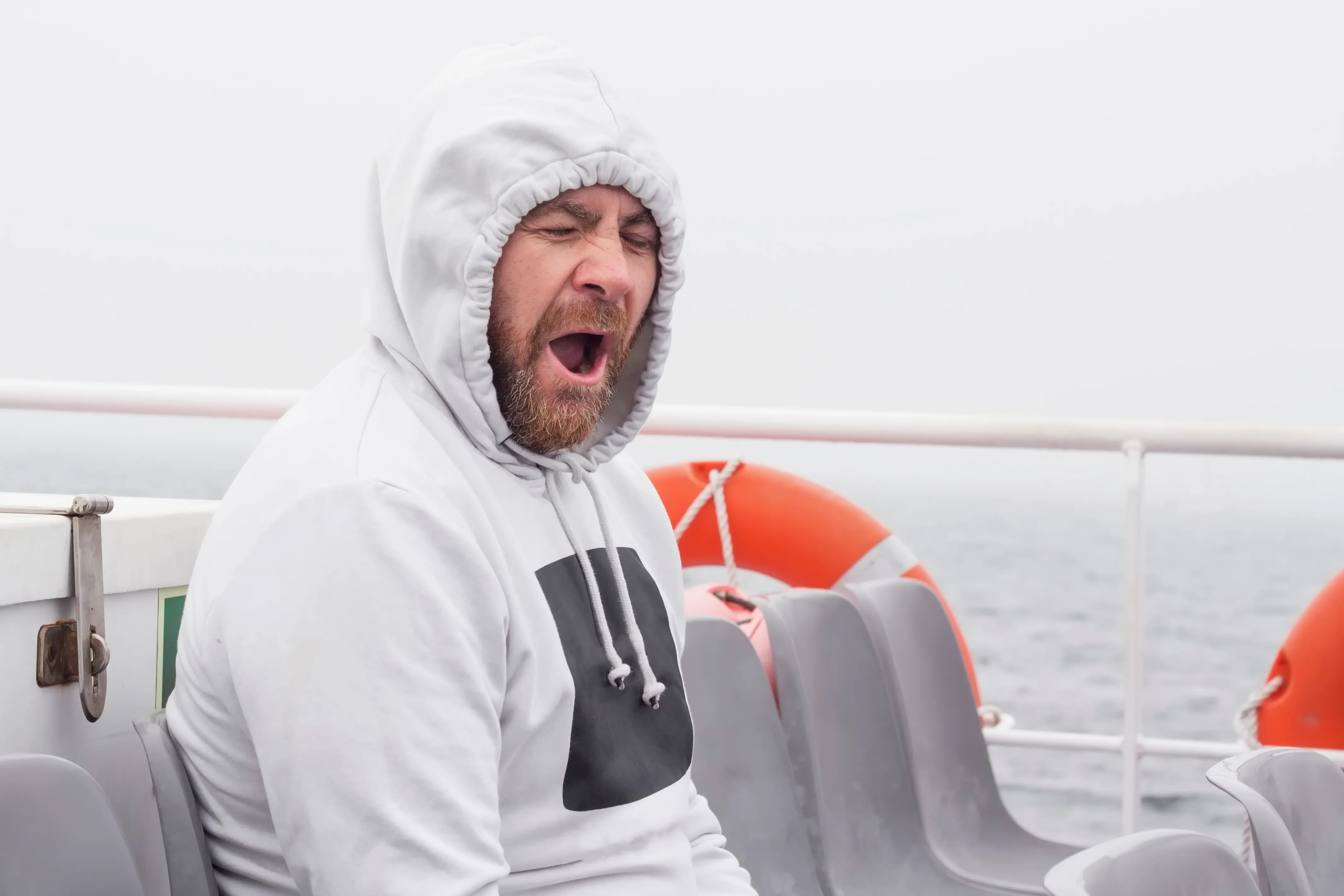 Yawning man seated on a boat