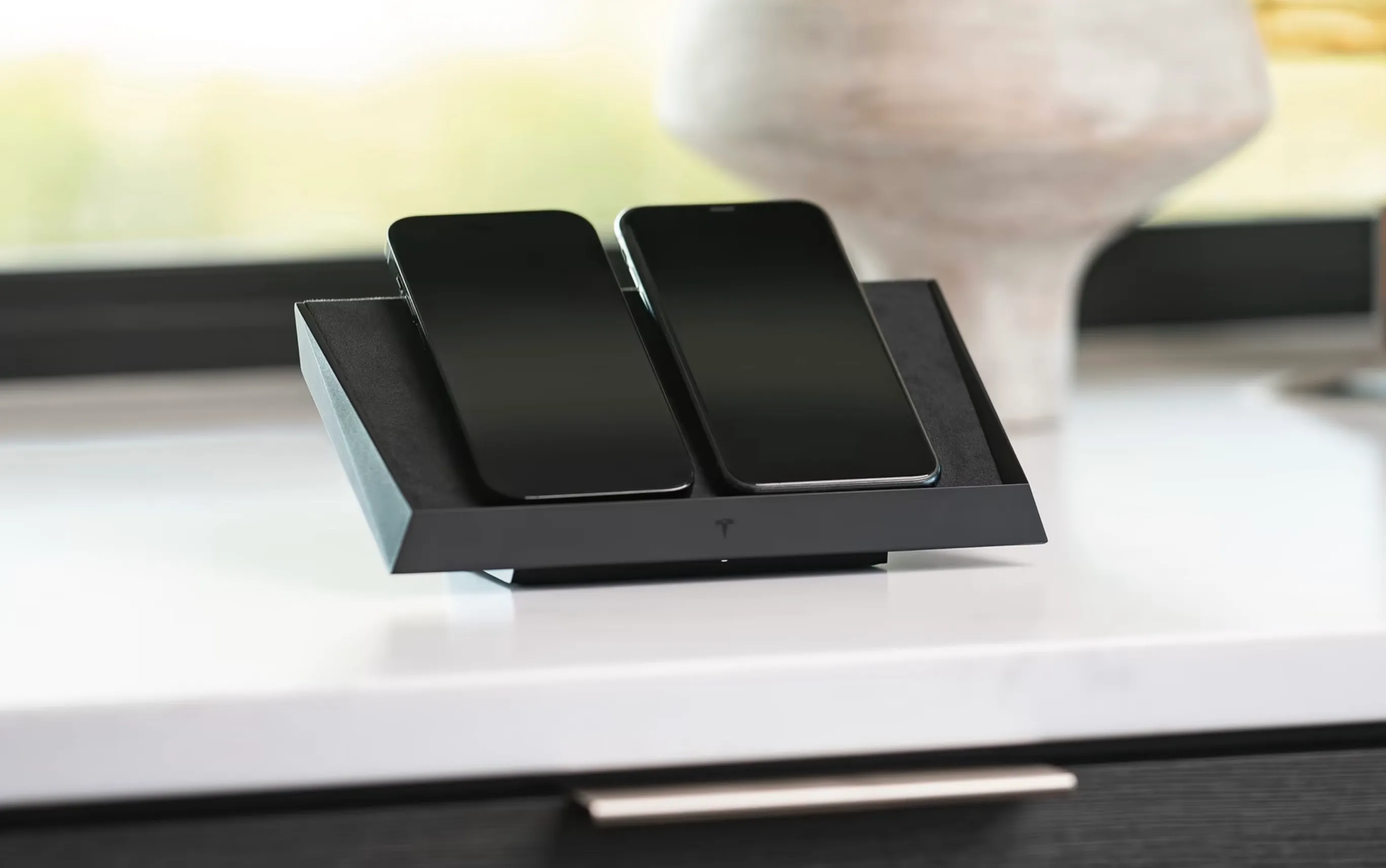 Tesla wireless charging station with 2 mobile phones on it