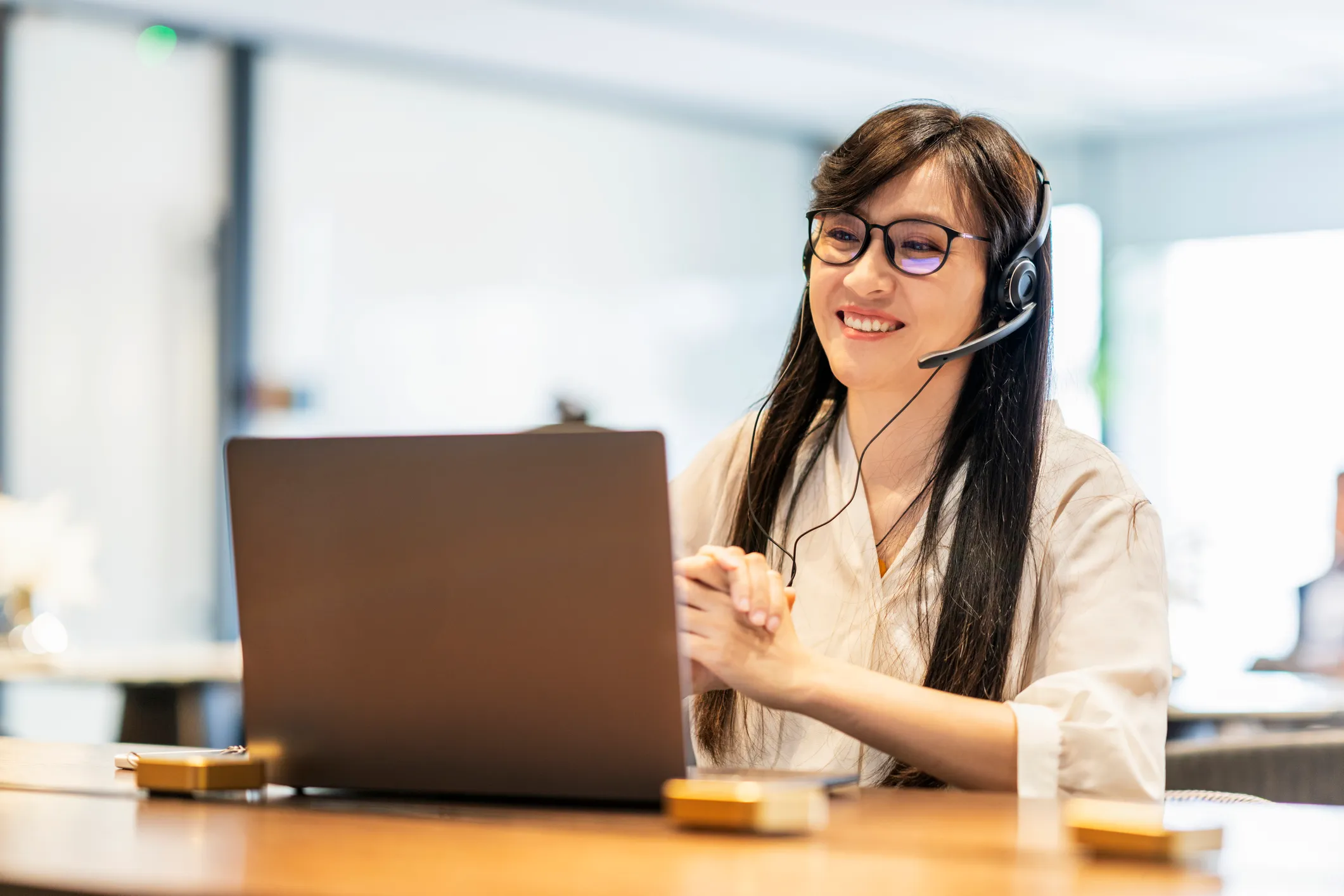 Woman sitting in front of a laptop with a headset, used in post about Attention.ai