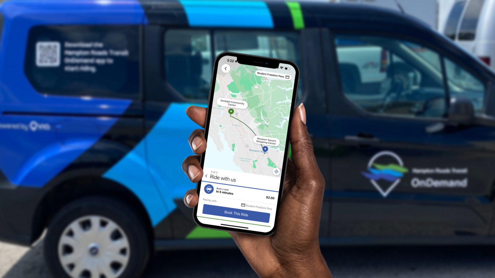 hand holding smartphone with transit app open. minivan in the background with via logo