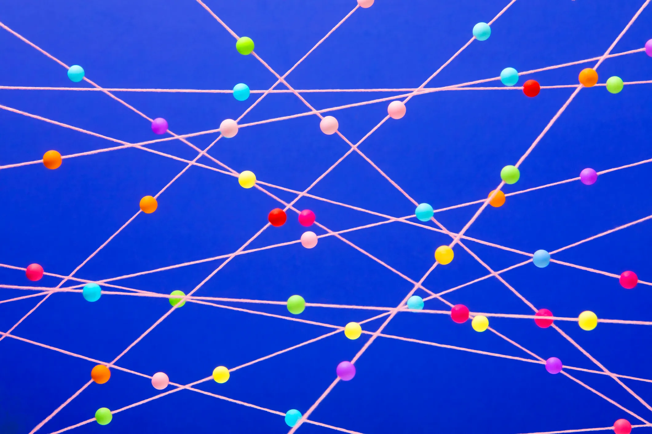 Bright multi colored balls randomly arranged on pink strings blue background, used in post about Betterdata