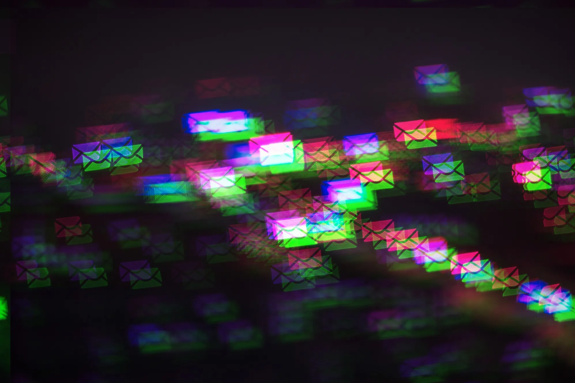 a pattern of multicolored photo-moshed envelopes flowing across on a dark background