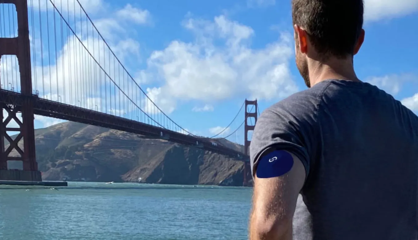 man wearing Signos glucose monitor staring at Golden Gate Bridge