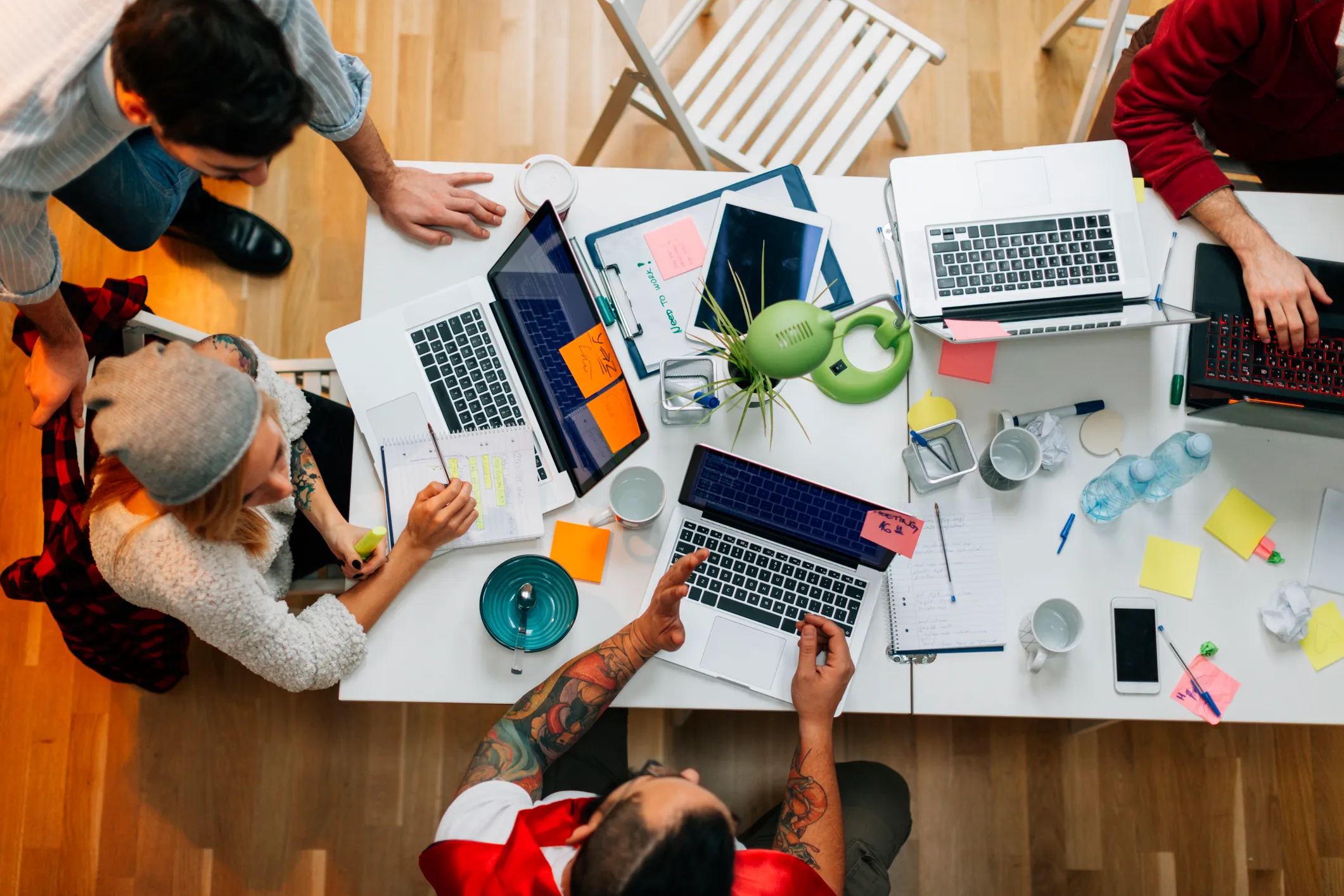 Overhead shot of team of startup developers working together at a table.