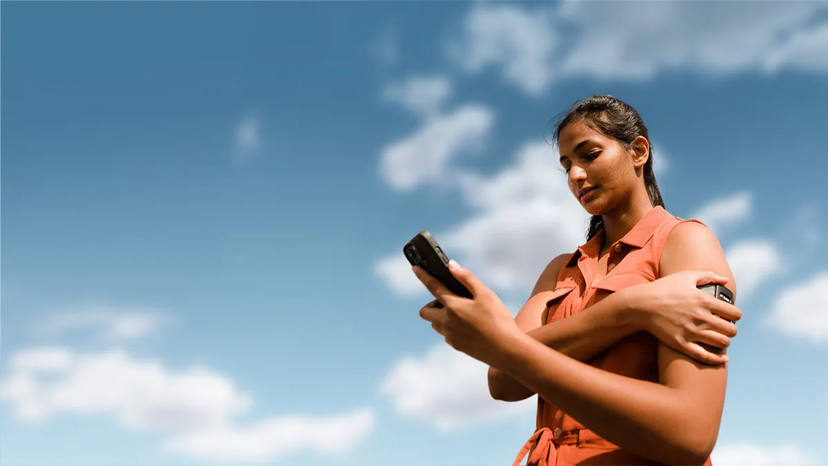 A woman is looking at her phone, wearing a Visible illness tracker