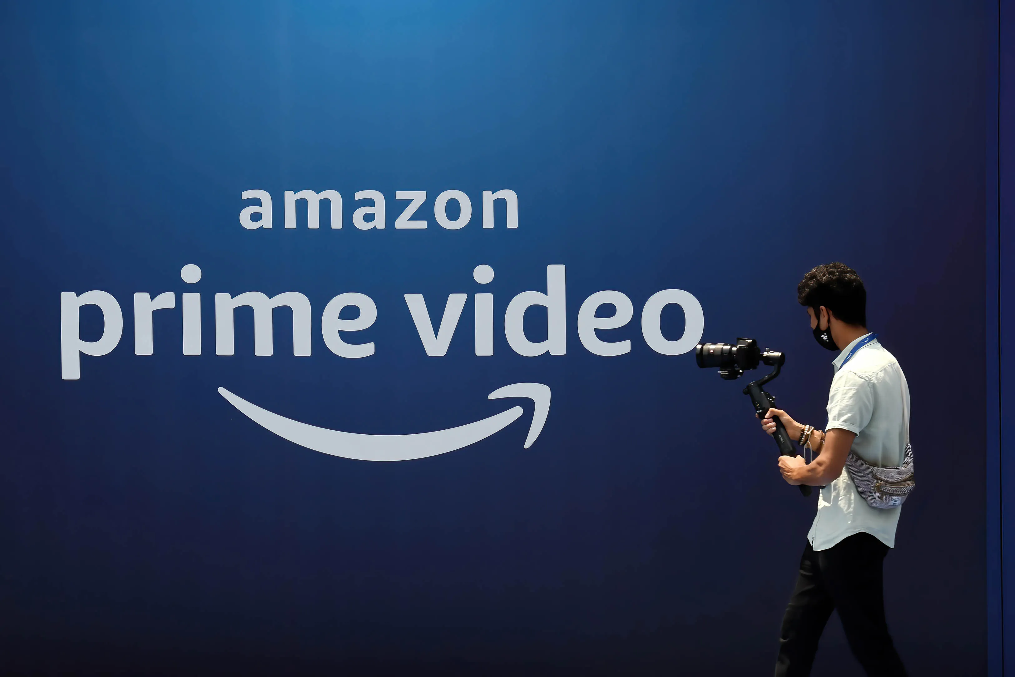 A cameraman records a video near the poster of Amazon Prime Video launch in Mumbai.