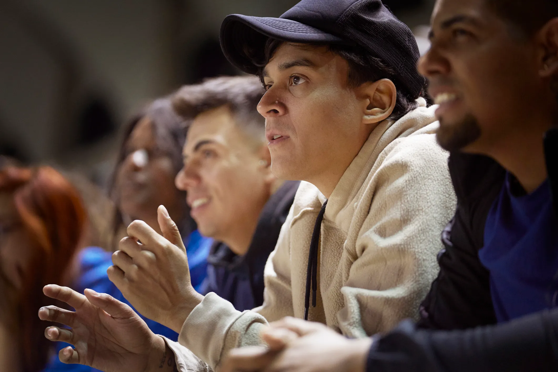 A young man anxiously watches a sporting event surrounded by a crowd of supporters all looking at a field. (Image Credits: Lighthouse Films/Getty Images)