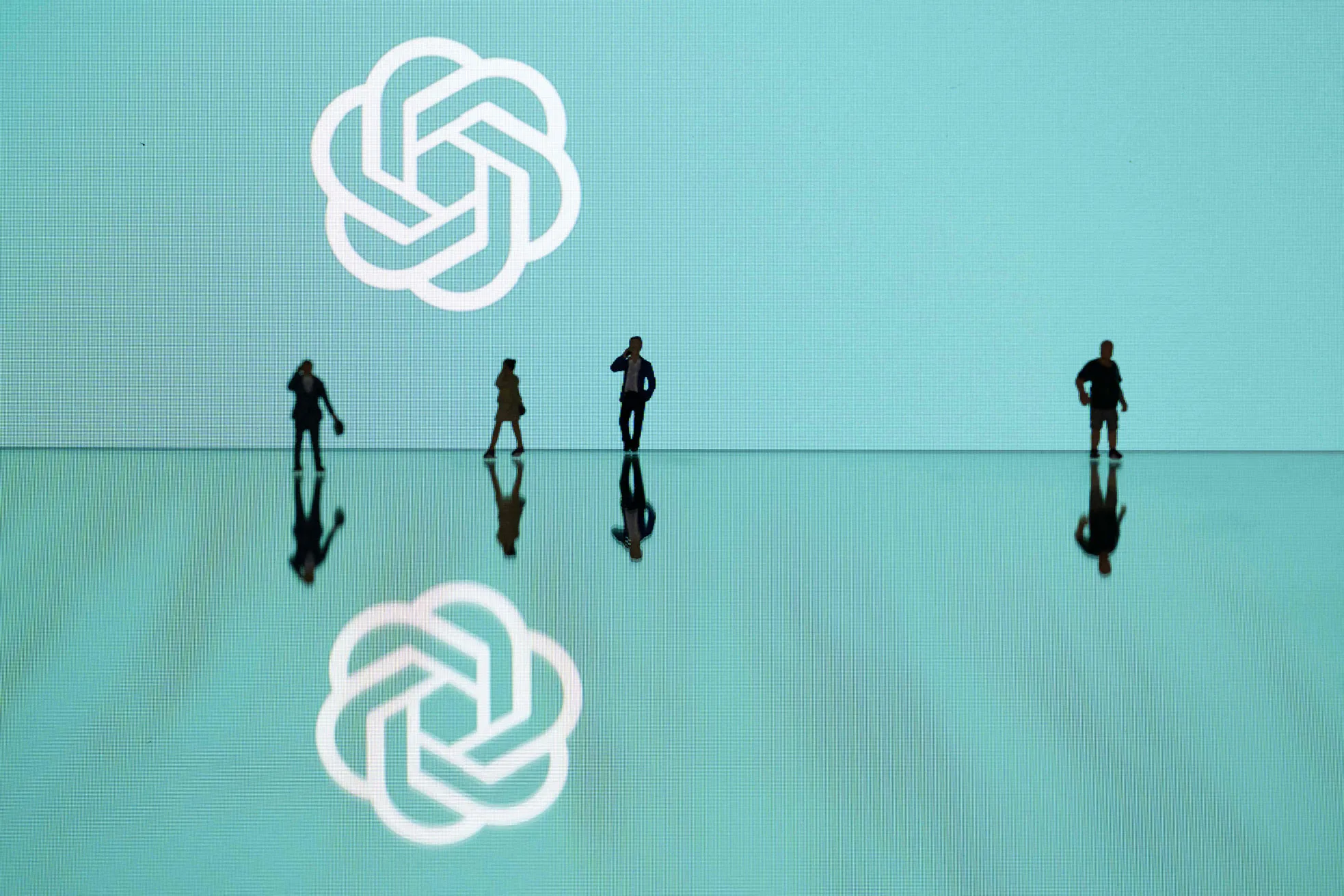 This photograph taken in Mulhouse, eastern France on October 19, 2023, shows figurines next to the ChatGPT logo. (Photo by SEBASTIEN BOZON/AFP via Getty Images)