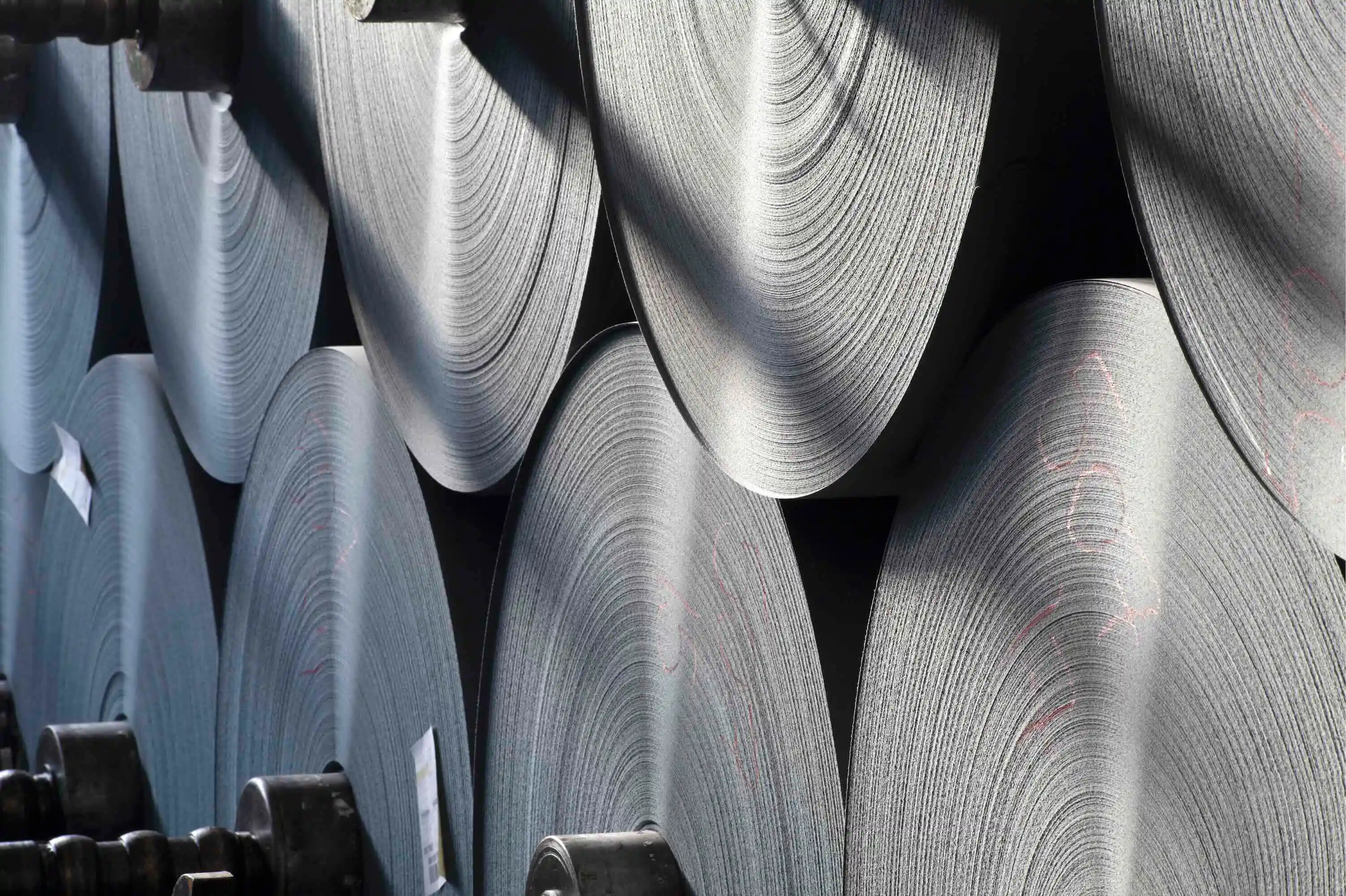 Large rolls of fresh paper sit stacked in a warehouse.