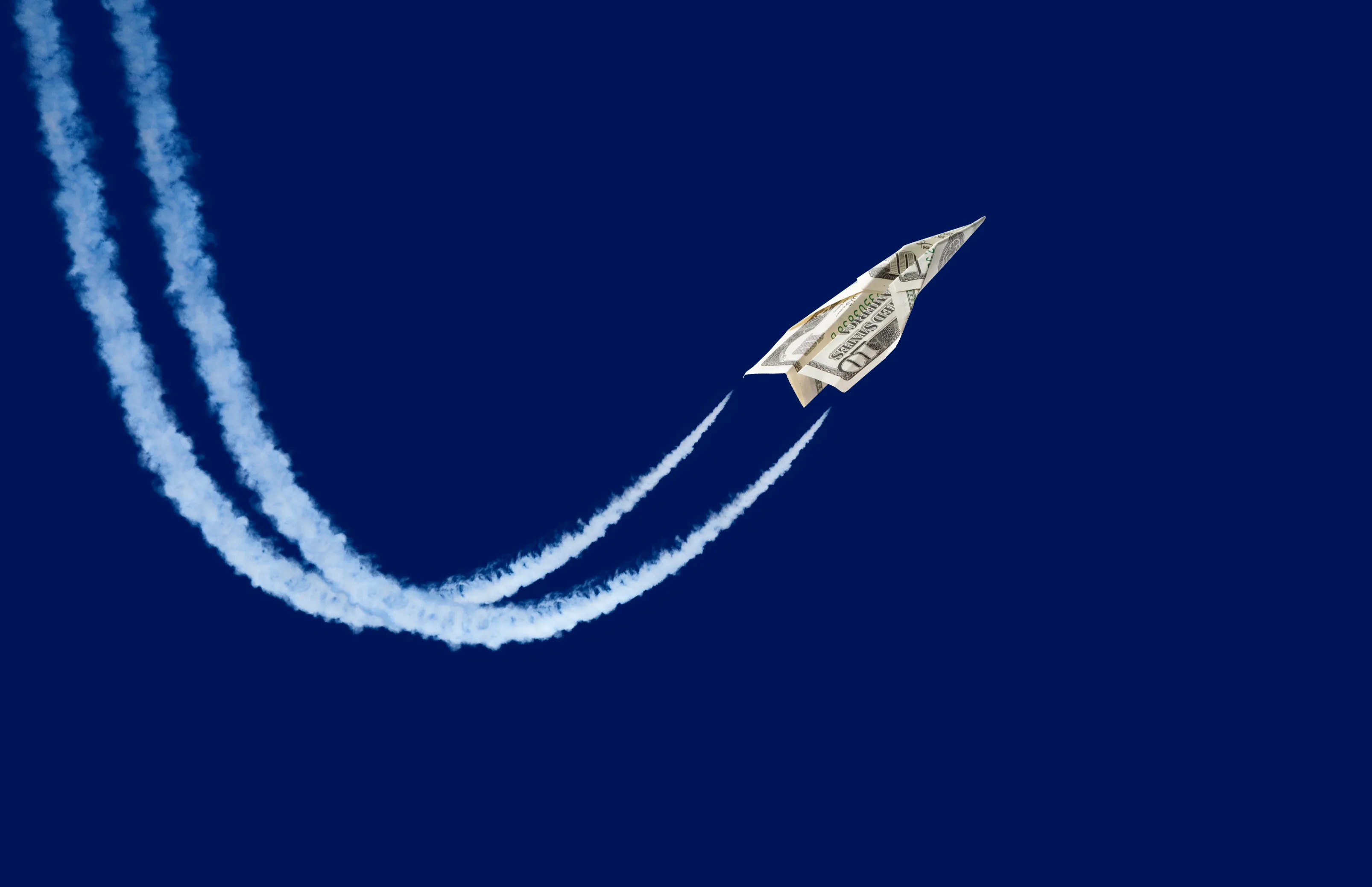 paper plane made from a ten-dollar bill 'flying' with contrails