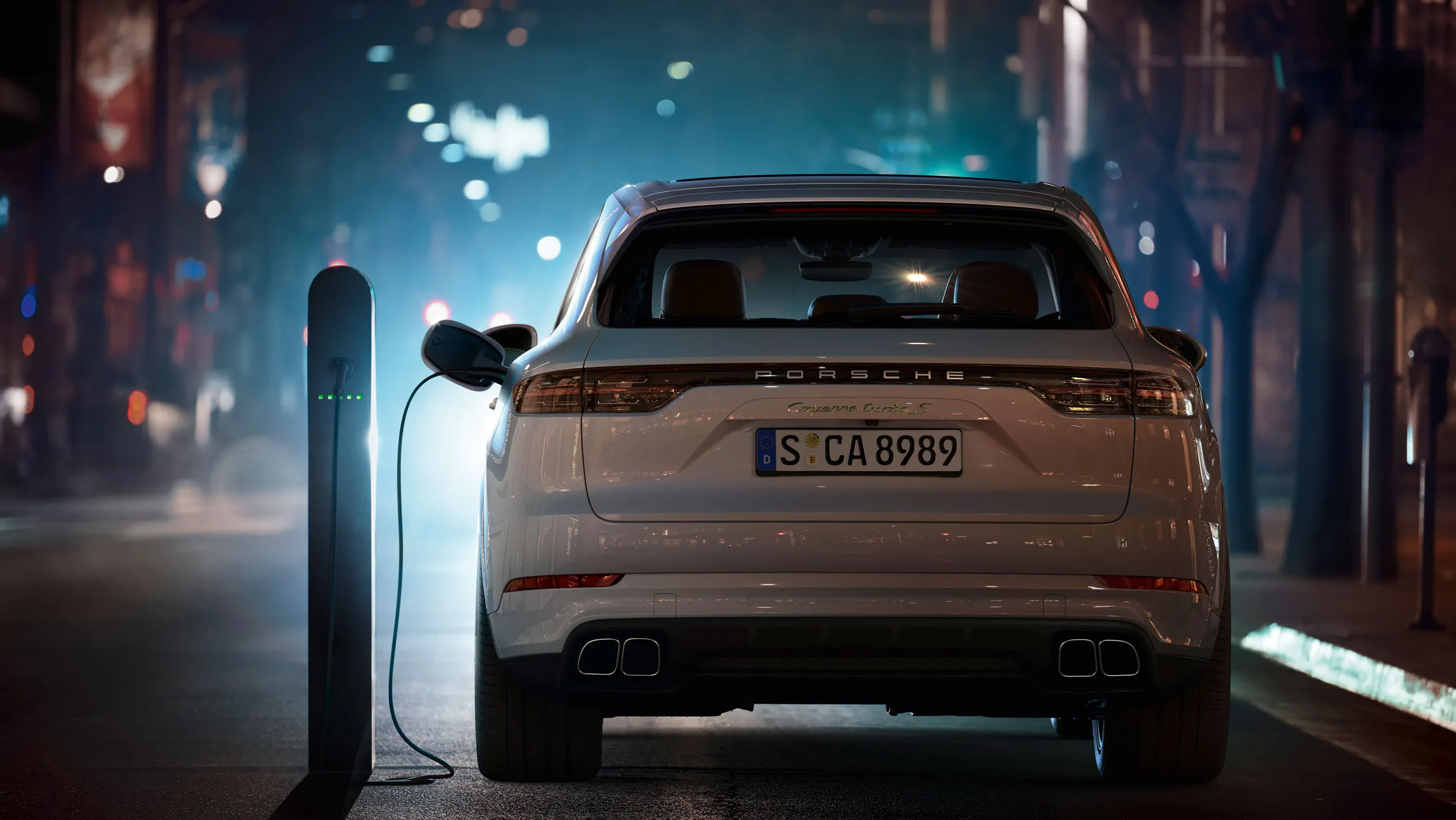 A PHEV SUV is plugged into a charger on the street.